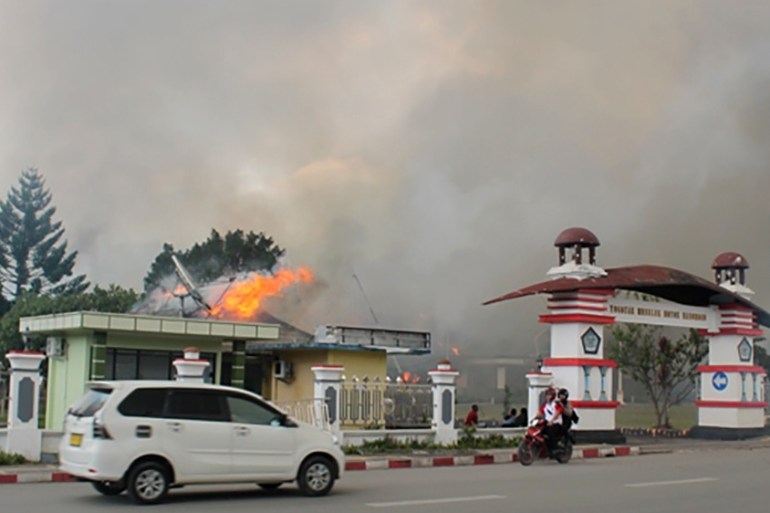 A car passes governor office building of Jayawijaya burned during a protest in Wamena, Papua