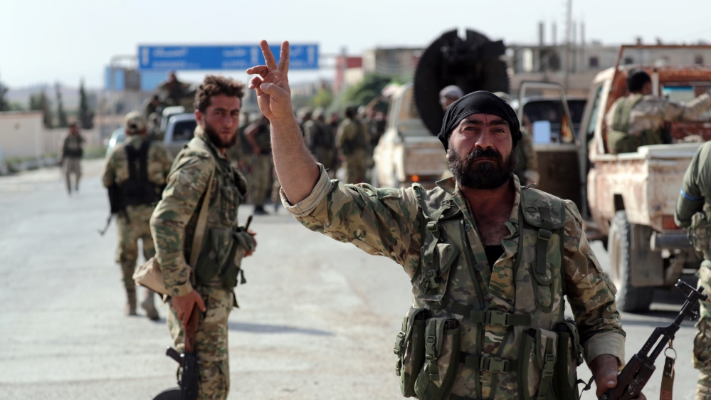 A Turkey-backed Syrian rebel fighter gestures to the camera at the border town of Tel Abyad, Syria, October 14, 2019