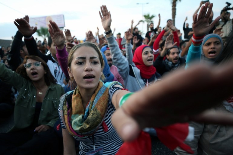 Demonstrators gesture as they block a road during ongoing anti-government protests in the port city of Sidon