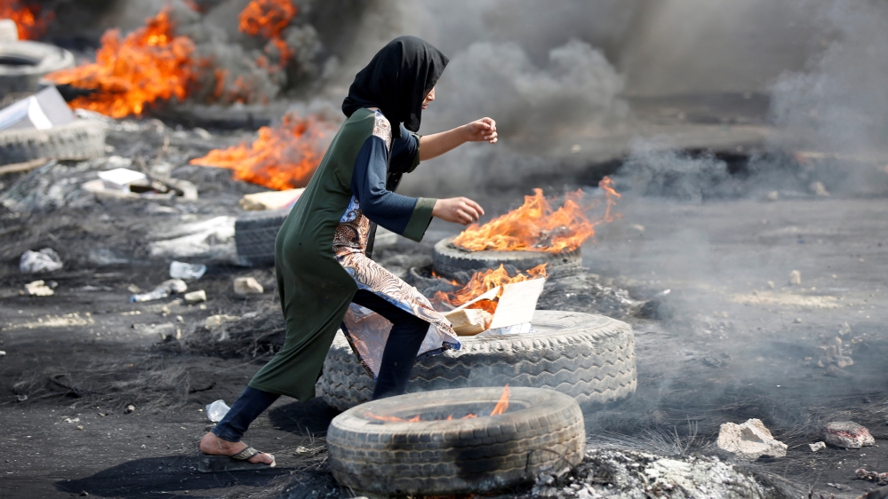 A demonstrator runs between burning tires during a curfew, two days after the nationwide anti-government protests turned violent, in Baghdad, Iraq October 3, 2019