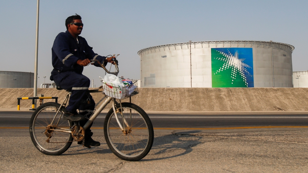 An employee rides a bicycle next to oil tanks at Saudi Aramco oil facility in Abqaiq