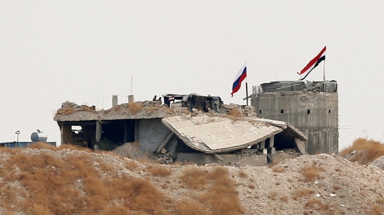 Russia Ukraine News_Russian and Syrian national flags are pictured near the northern Syrian village of Zor Magar, as seen from the Turkish border town of Karkamis