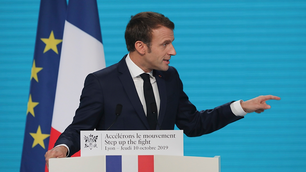 France's President Emmanuel Macron gestures as he delivers a speech at the Lyon's congress hall, central France, Thursday, Oct. 10, 2019, during the meeting of international lawmakers, health leaders 