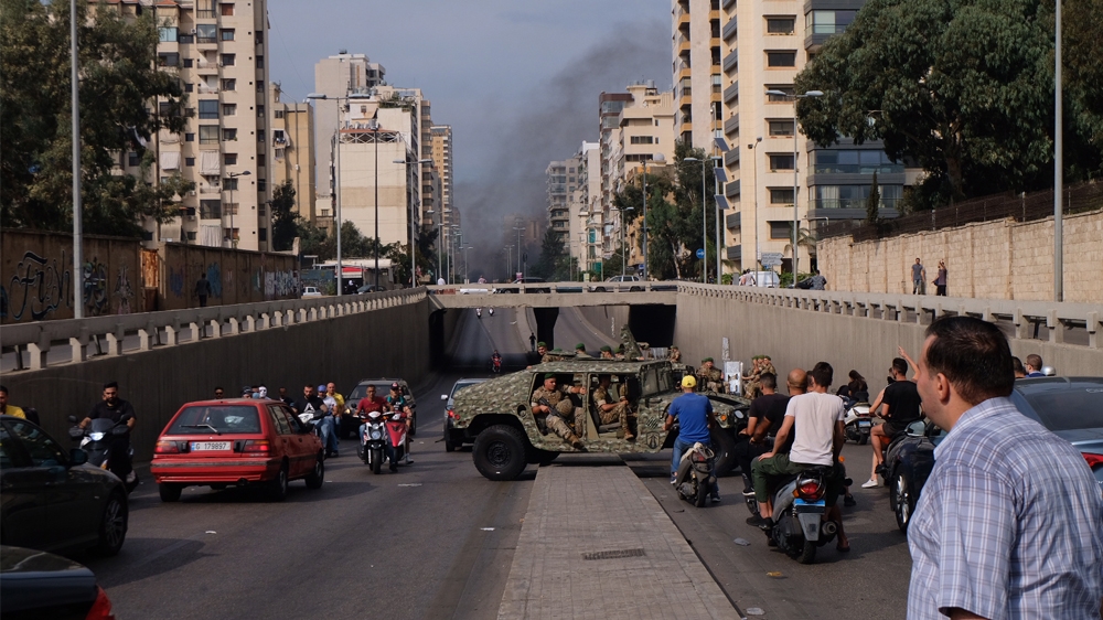 A convoy of Army Humvees turns around after being confronted by protestors at a roadblock oustide central Beirut [Timour Azhari/Al Jazeera]