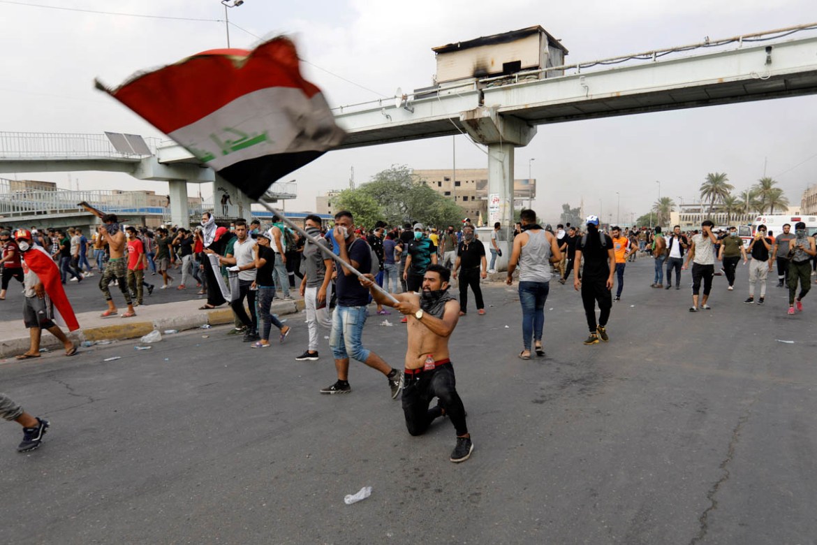 A demonstrator holds the Iraqi flag as at a protest over unemployment, corruption and poor public services, in Baghdad, Iraq October 2, 2019. REUTERS/Khalid al-Mousily