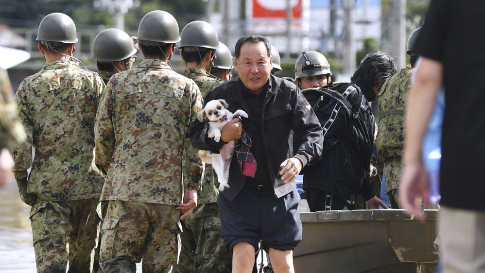 A local resident carrying his pet dog evacuates from an area flooded by the Abukuma river following Typhoon Hagibis in Motomiya