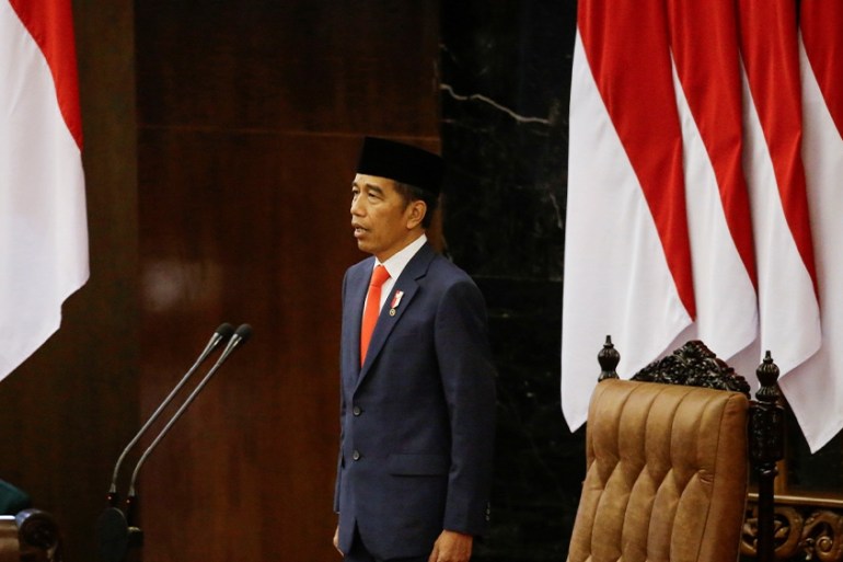 Indonesian President Joko Widodo stands in front of an Indonesian flag