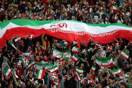 Iranian women cheer as they hold a huge Iranian flag during a soccer match between their national team and Cambodia in the 2022 World Cup qualifier at the Azadi (Freedom) Stadium in Tehran, Iran, Thur