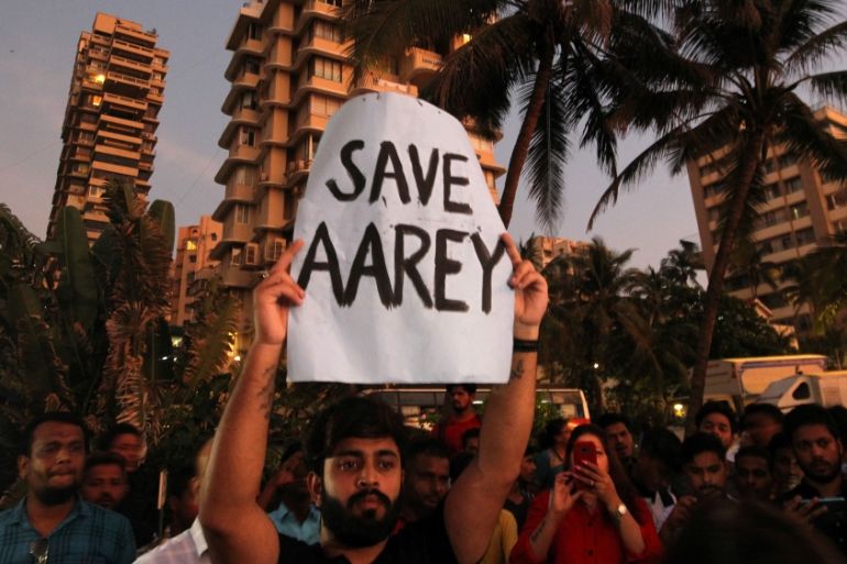 A man displays a placard at a promenade during a protest demanding that MMRCL not cut trees to build a train parking shed for an upcoming subway line, in Mumbai