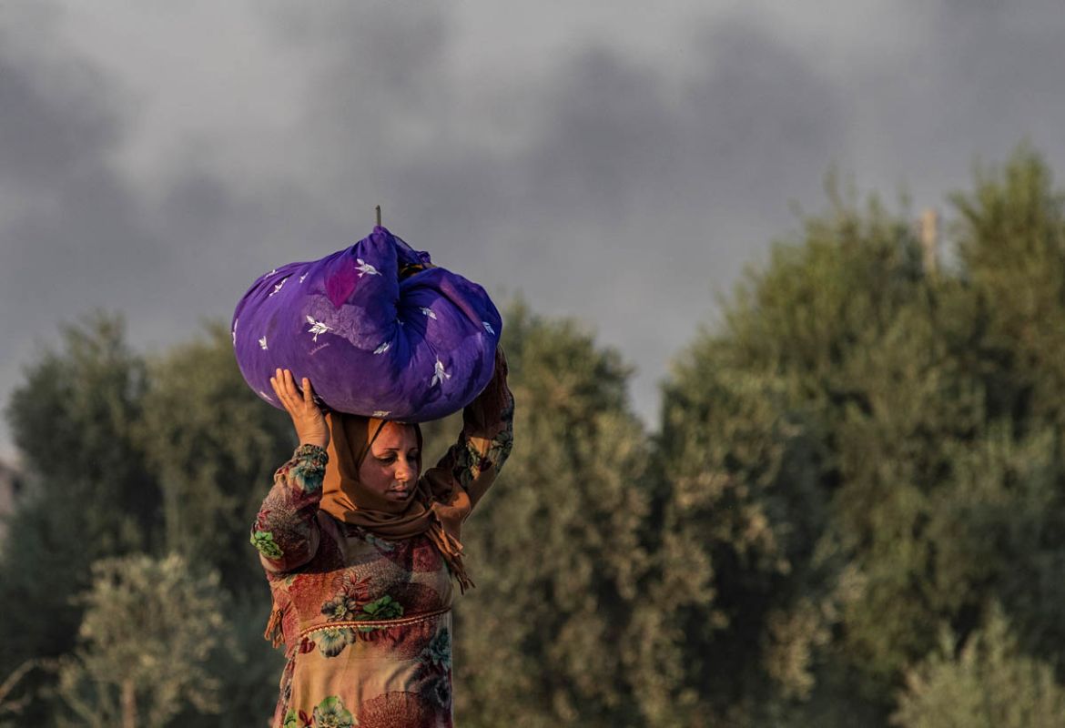 A Syrian woman carries her belongings over her head as she flees amid Turkish bombardment on Syria''s northeastern town of Ras al-Ain in the Hasakeh province along the Turkish border on October 9, 2019