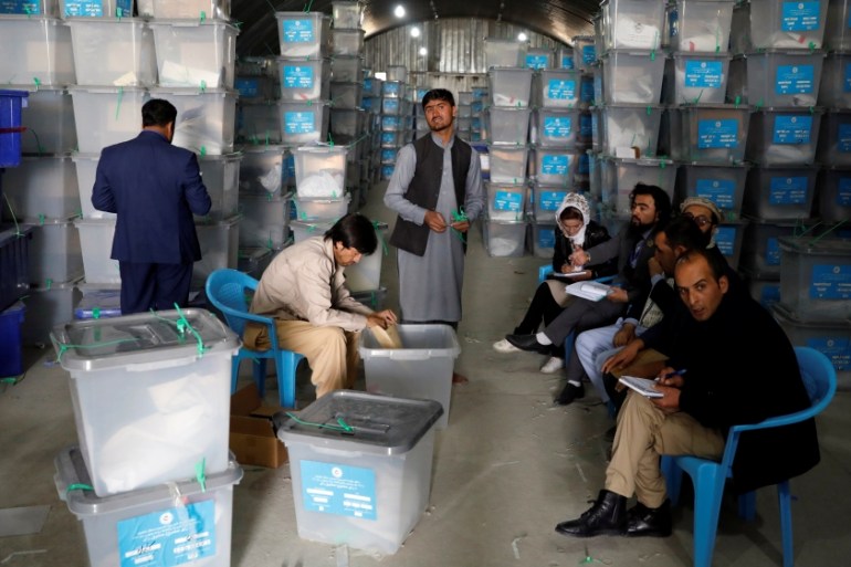 Afghan election commission worker opens ballot boxes and election materials at a warehouse in Kabul