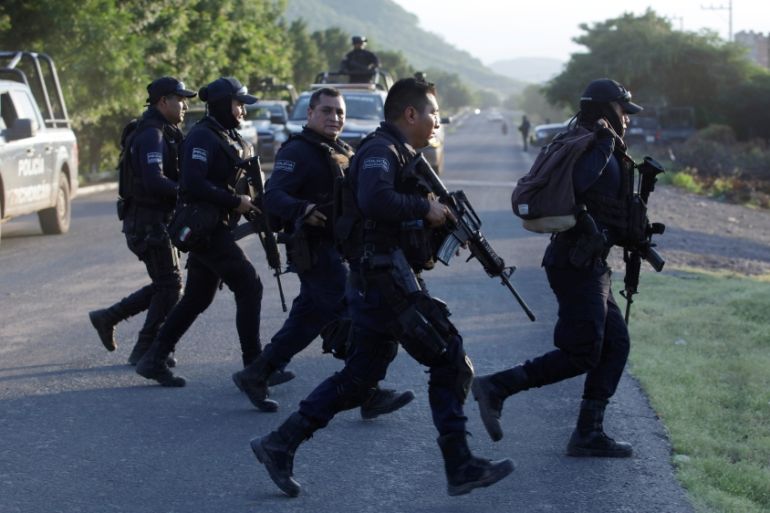 Police officers patrol at a road after fellow police officers were killed during an ambush by suspected cartel hitmen in El Aguaje