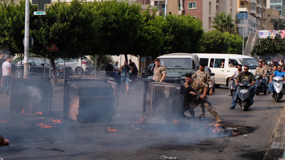 A soldier tried to clear a path through smoldering garbage bins and flaming tires on the outskirts of downtown Beirut  [Timour Azhari/Al Jazeera]