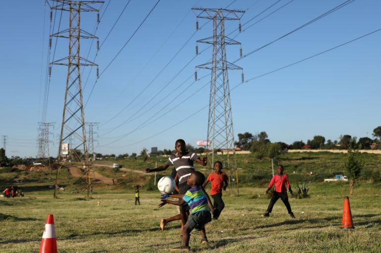 Boys use traffic cones as goal posts as the play soccer below electricity pylons in Soweto