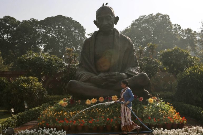 A worker waters plants around a statue of Mahatma Gandhi in New Delhi, India