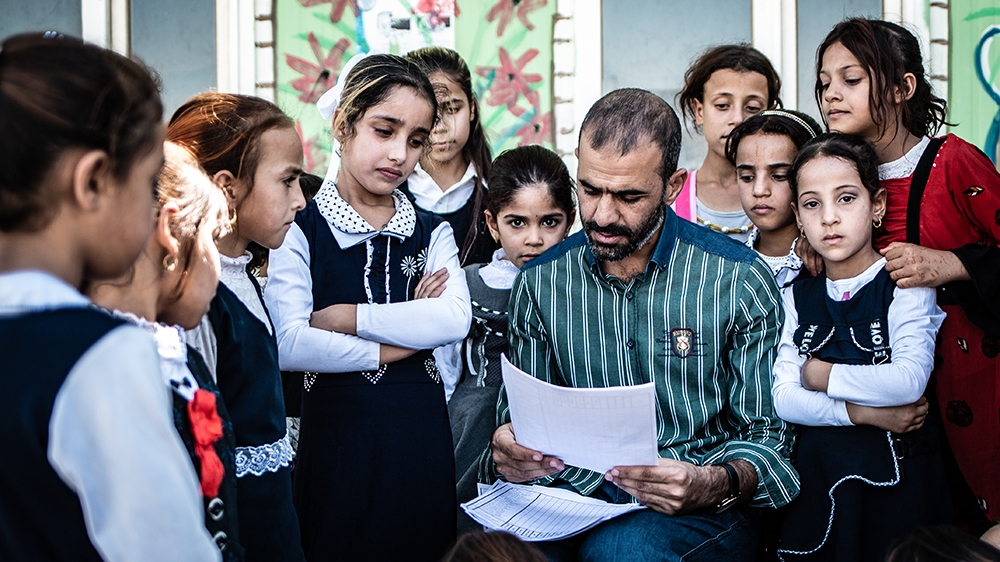 A teacher counting students in the schoolyard due to a lack of school building - back to school day 2019-2020 in Aljaleel school, Mosul [Tom Peyre-Costa/NRC]