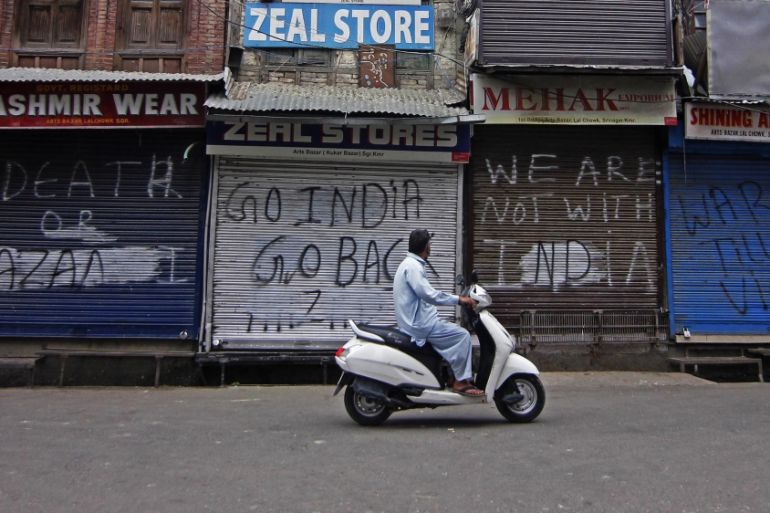 A man rides a scooter in front of a closed shop after the Government tightened restrictions in most parts of the Kashmir, India ahead of scheduled speeches by world leaders including Indian and Pakist
