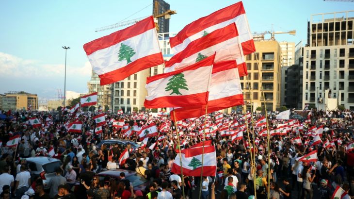 Demonstrators carry national flags during an anti-government protest in downtown Beirut