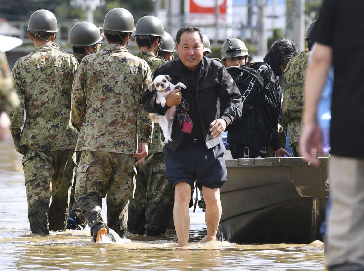 A local resident carrying his pet dog evacuates from an area flooded by the Abukuma river, caused by Typhoon Hagibis, in Motomiya, Fukushima prefecture, Japan, October 13, 2019, in this photo taken by