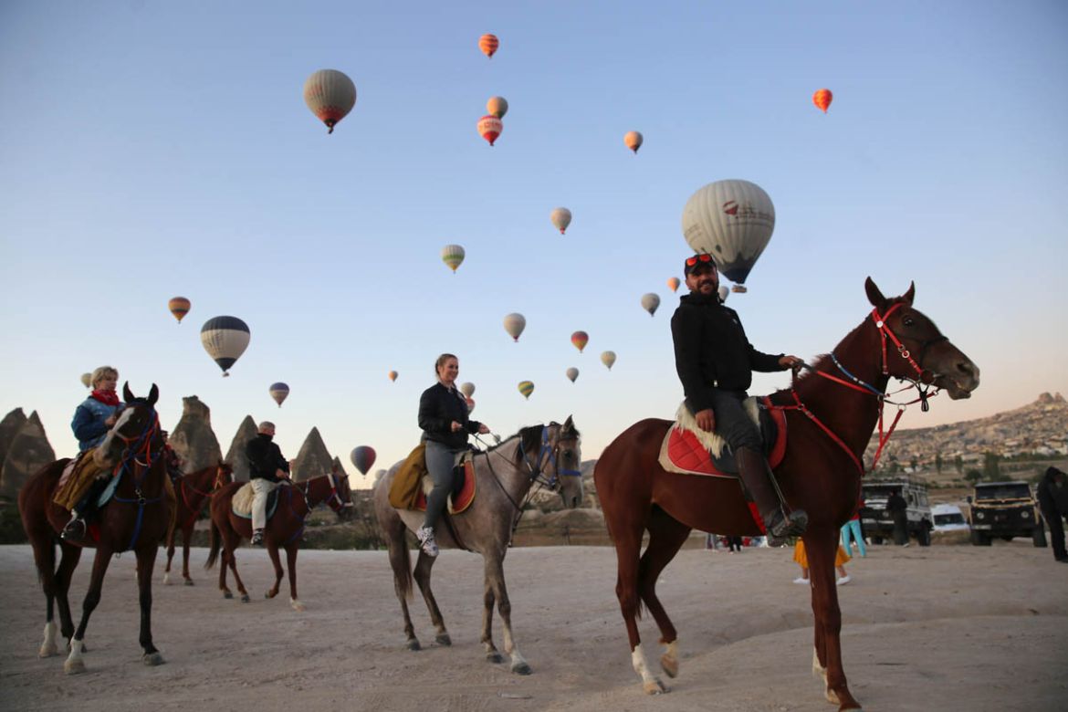 Visitors ride horses as hot air balloons glide over Goreme district during early morning at the historical Cappadocia region, located in Central Anatolia''s Nevsehir province, Turkey on September 23, 2