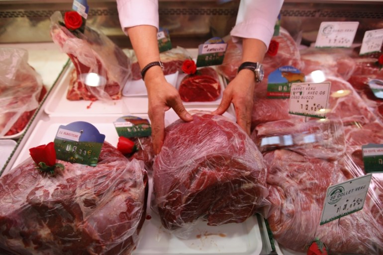 A butcher arranges pieces of meat at his shop in Marseille, France