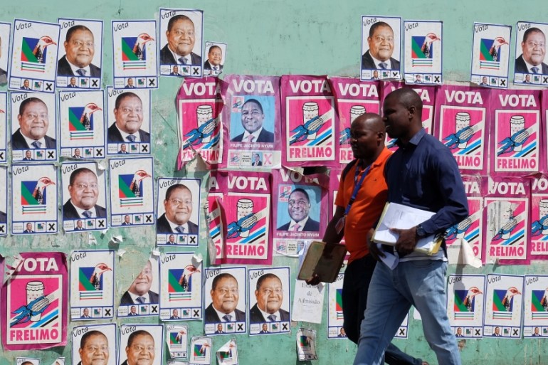 Mozambicans walk past election posters ahead Tuesday''s provincial and legislative elections