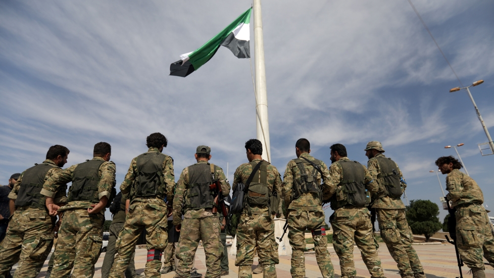 Turkey-backed Syrian rebel fighters raise the Syrian opposition flag at the border town of Tel Abyad, Syria, October 14, 2019