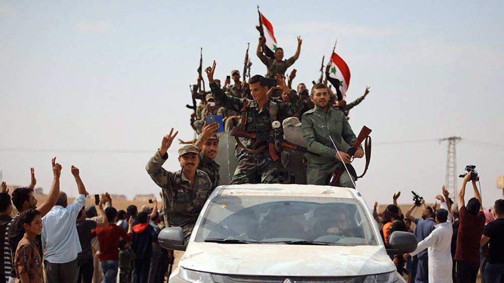 Syrian army soldiers gesture as they stand in vehicles in the town of Ain Issa, Syria, in this handout released by SANA on October 14, 2019. SANA/Handout via REUTERS ATTENTION EDITORS - THIS IMAGE WAS