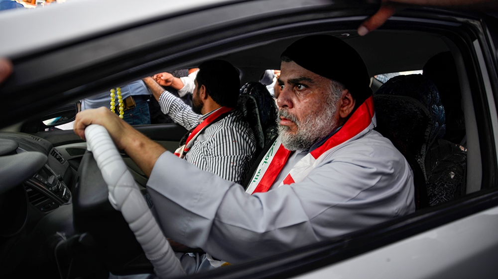 Iraqi Shiite cleric Moqtada al-Sadr (R) drives a car as he joins anti-government demonstrators gathering in the central holy city of Najaf on October 29, 2019. - Sadr, who has backed the protests, was