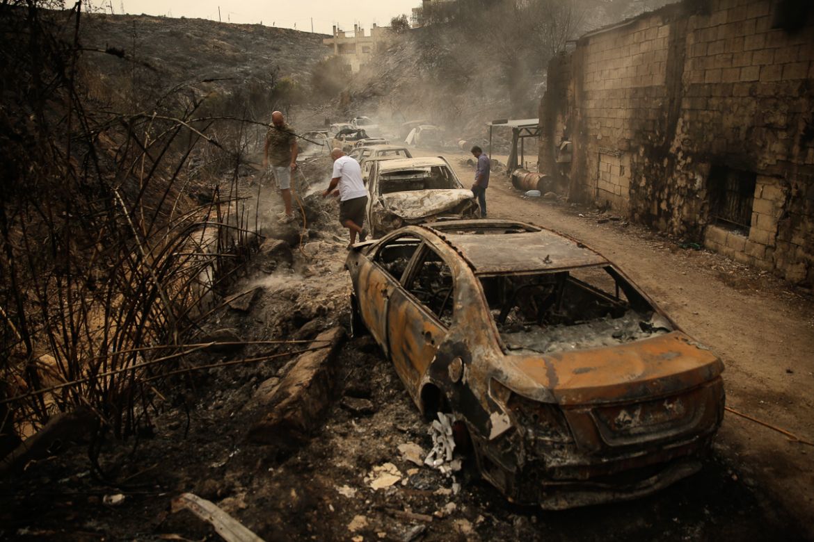 People inspect the remains of cars and shops that were burned in a wildfire overnight, in the town of Damour just over 15km (9 miles) south of Beirut, Lebanon, Tuesday, Oct. 15, 2019. Strong fires spr