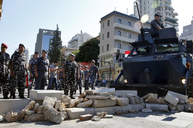 Police remove stones set up by anti-government protesters to block a main road in Beirut, Lebanon, Wednesday, Oct. 30, 2019. There was so significant resistance from protesters as army units with bull