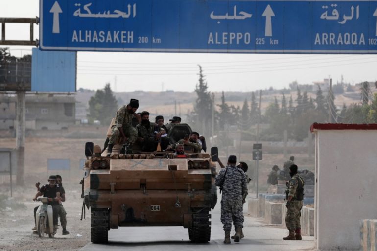 Turkey-backed Syrian rebel fighters sit on a military truck at the border town of Tel Abyad, Syria, October 14, 2019.