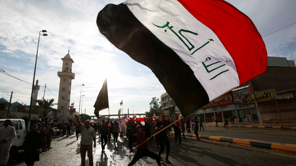 A demonstrator holds an Iraqi flag during a protest over corruption, lack of jobs, and poor services, in Najaf, Iraq October 25, 2019