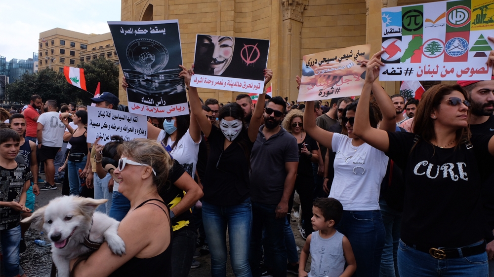 Protestors hold placards calling out the political establishment in downtown Beirut  [Timour Azhari/Al Jazeera]