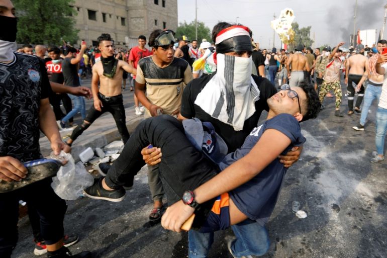 A man carries away a demonstrator, injured during a protest over unemployment, corruption and poor public services, in Baghdad