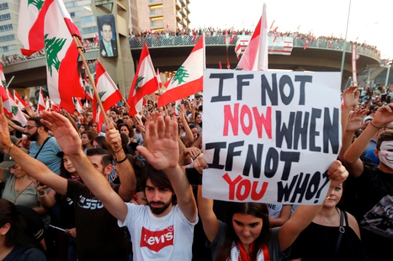 Demonstrators carry national flags and banners during an anti-government protest along a highway in Jal el-Dib