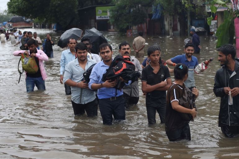 People wade through a flooded road after a heavy rainfall in Mumbai