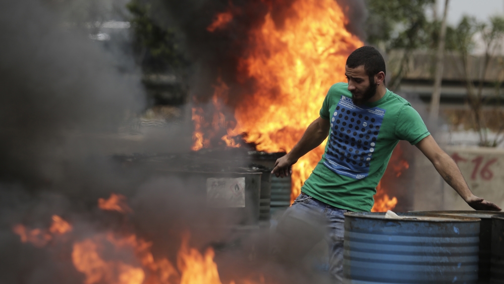 An anti-government protester sets fire to tires to block a highway that links the capital Beirut to northern Lebanon during a protest against the Lebanese government in Zouk Mosbeh, north of Beirut, L