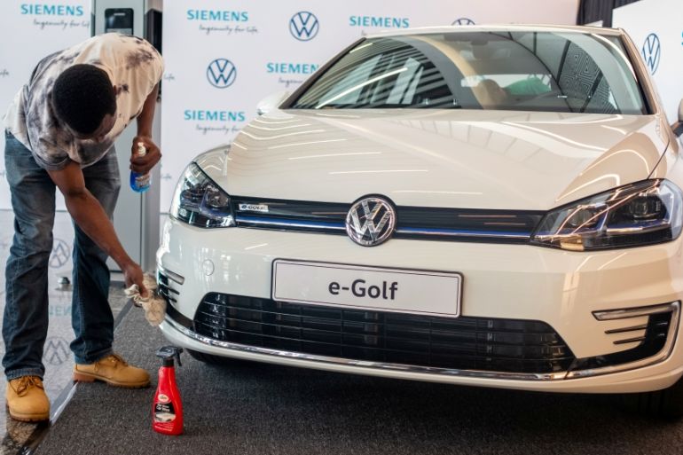 A worker cleans a Volkswagen e-Golf electric car during its launch for use in its ride-hailing service in Kigali
