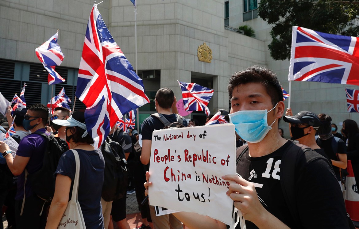 A man holds a placard as a group of Hong Kong residents waving U.K. flags demonstrate requesting right to British residency, Tuesday, Oct. 1, 2019, outside the British embassy in Hong Kong while the c
