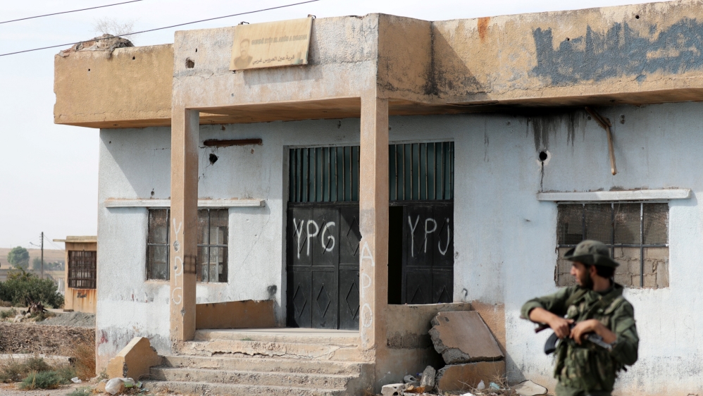 Turkey-backed Syrian rebel fighter stands near a former YPG office at the entrance of Tel Abyad, Syria, October 14, 2019