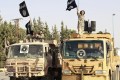 Militant Islamist fighters wave flags as they take part in a military parade along the streets of Raqqa