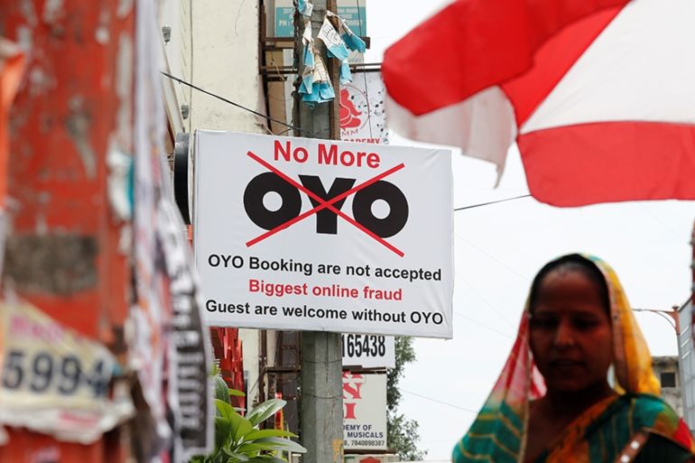 A woman walks pasts a sign against Oy, placed outside a hotel in New Delhi, India, August 7, 2019. Picture taken August 7, 2019