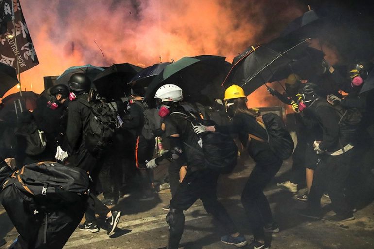 Students use umbrellas as a shield during a clash with police at the Chinese University in Hong Kong, Tuesday, Nov. 12, 2019. Police and protesters battled outside university campuses and several thou