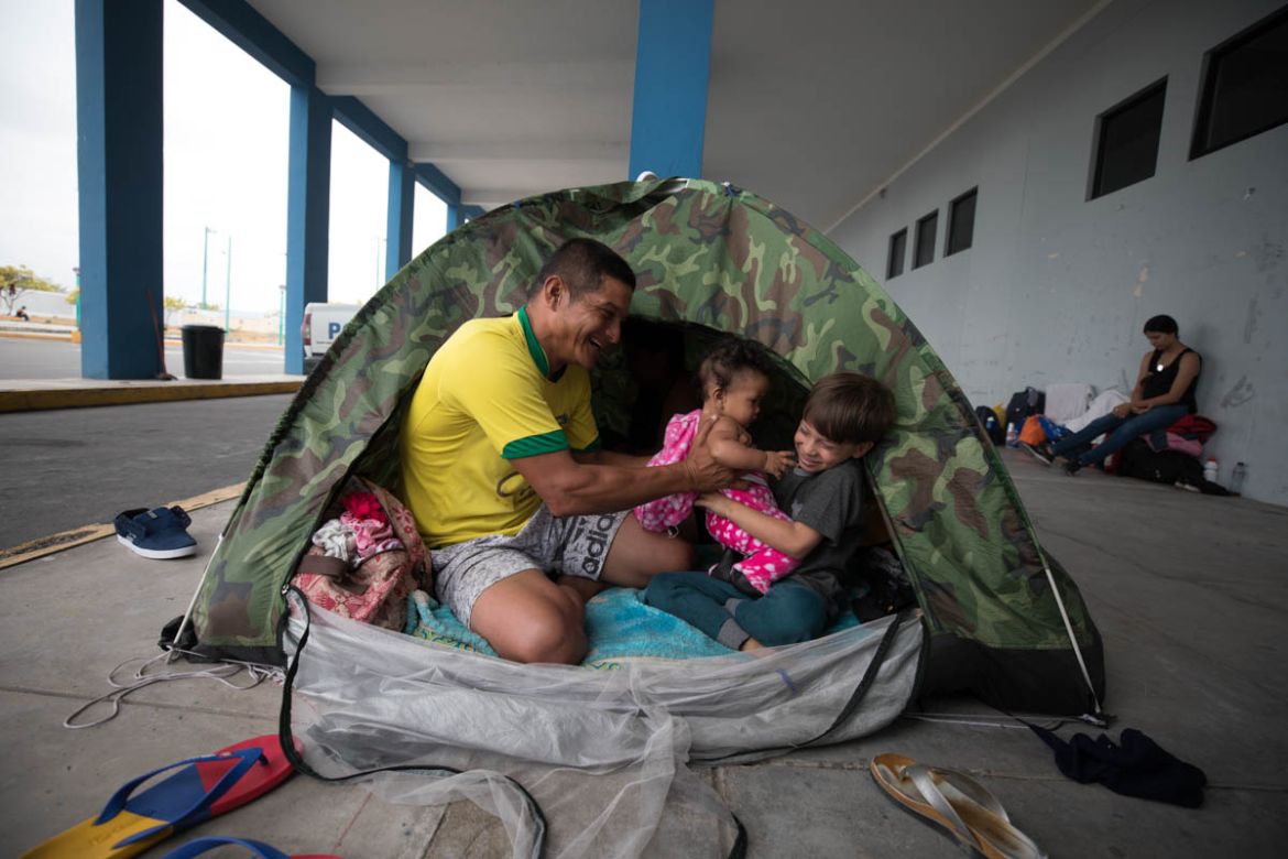Cesar plays with his daughter and nephew in a makeshift tent on the border between Ecuador and Peru. The former mechanic left the country with his family when his salary could no longer feed his famil