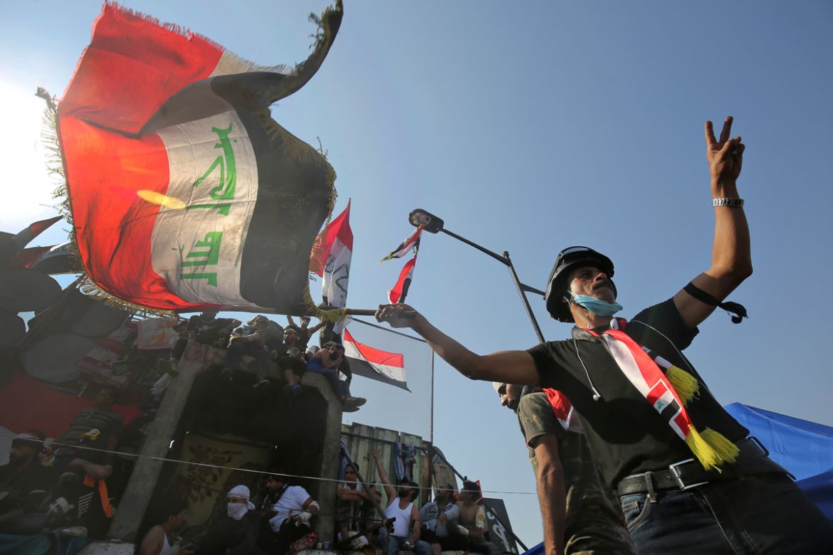 An Iraqi demonstrator waving a national flag flashes the victory sign near al-Jumhuriya bridge which leads to the high-security Green Zone, during ongoing anti-government protests in the capital Baghd