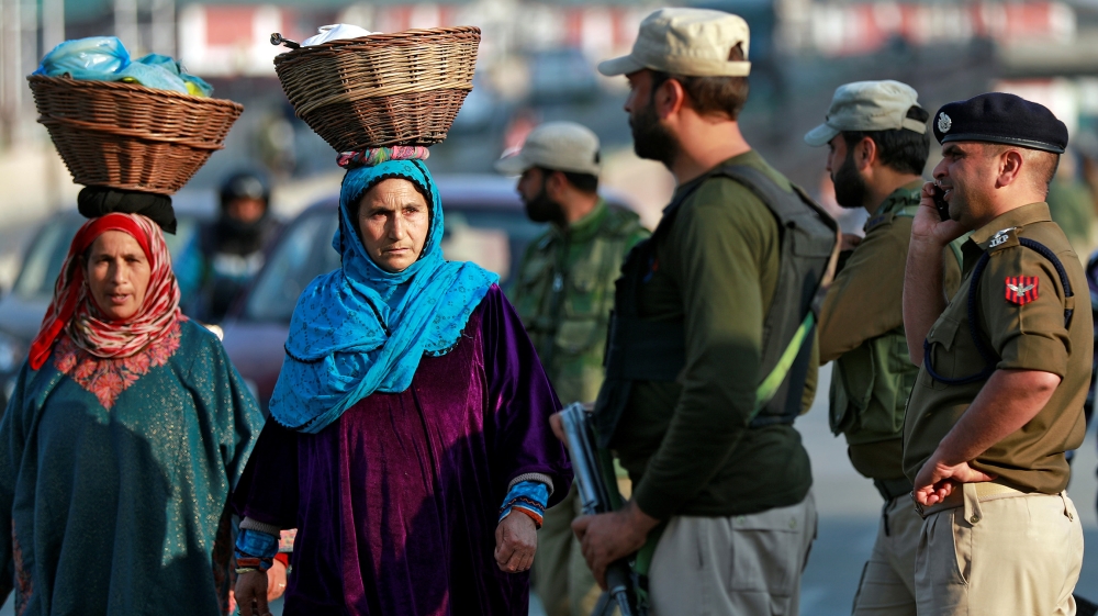Kashmiri women walk past Indian policemen standing guard in a street in Srinagar October 31, 2019. REUTERS/Danish Ismail