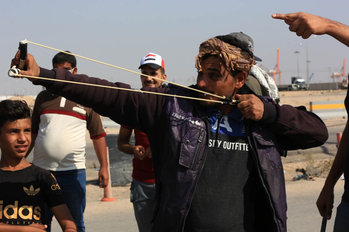 An anti-government protester fires a slingshot as they block the port of Umm Qasr during ongoing anti-government protests, in Basra, Iraq, Sunday, Nov. 3, 2019. (AP Photo/Nabil al-Jourani)
