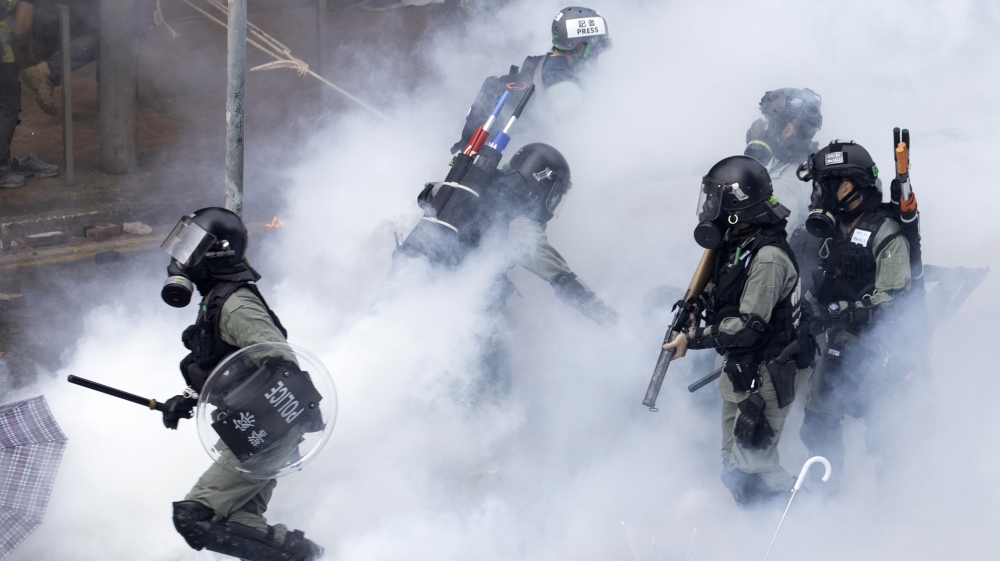 Police in riot gear move through a cloud of smoke at the Hong Kong Polytechnic University in Hong Kong, Monday, Nov. 18, 2019