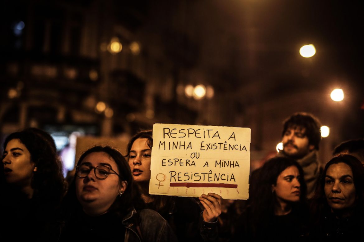 A woman holds a banner with the words ''Respect my existence or expect my resistance'' and shouts slogans during the march marking the International Day for the Elimination of Violence against Women in